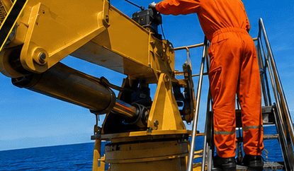 Técnico sobre guindaste em operação no mar